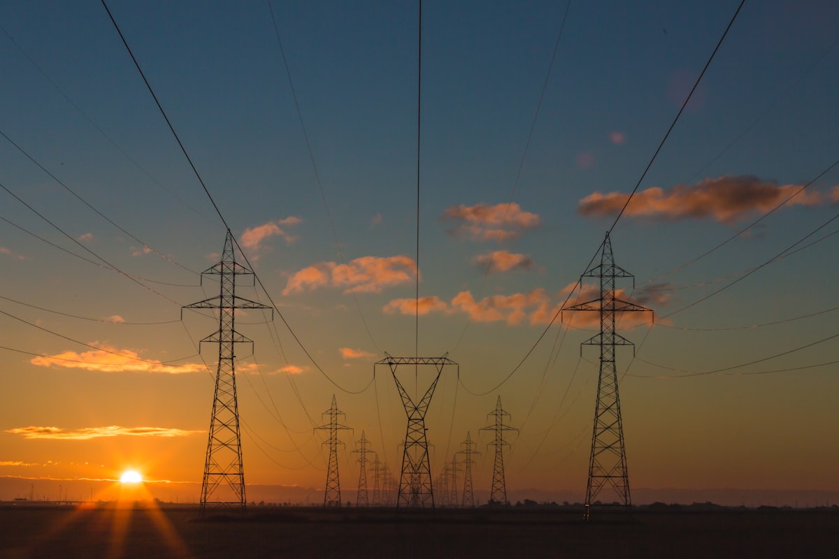 High-voltage electricity transmission pylons and power lines at sunset